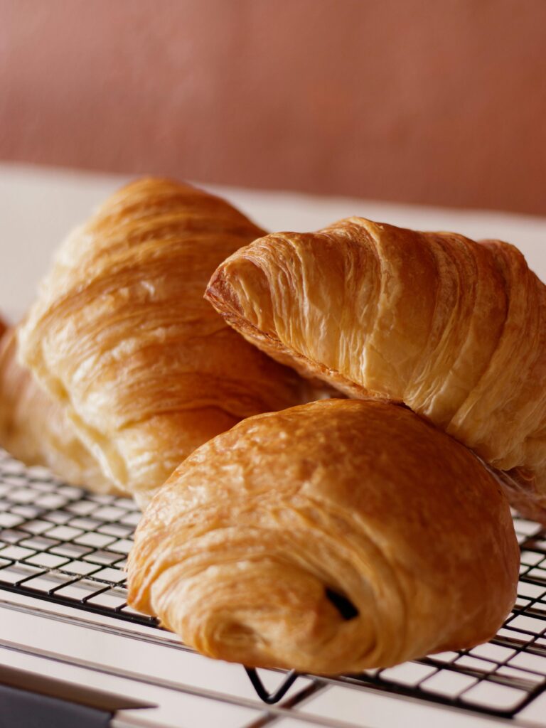 Golden croissants cooling on a rack, highlighting flaky layers and texture.